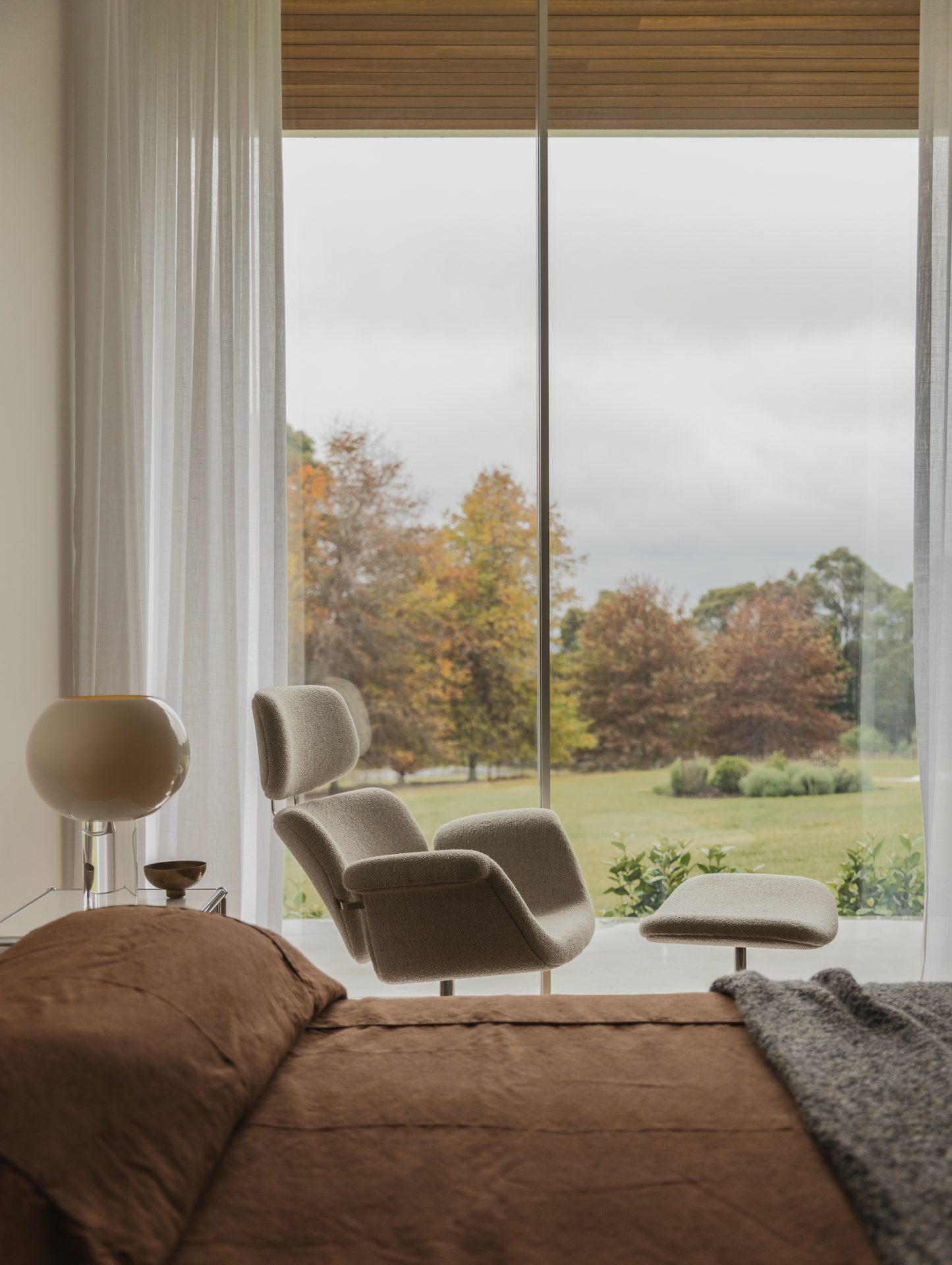 Lounge chair beside a picture window overlooking the garden at Melody House